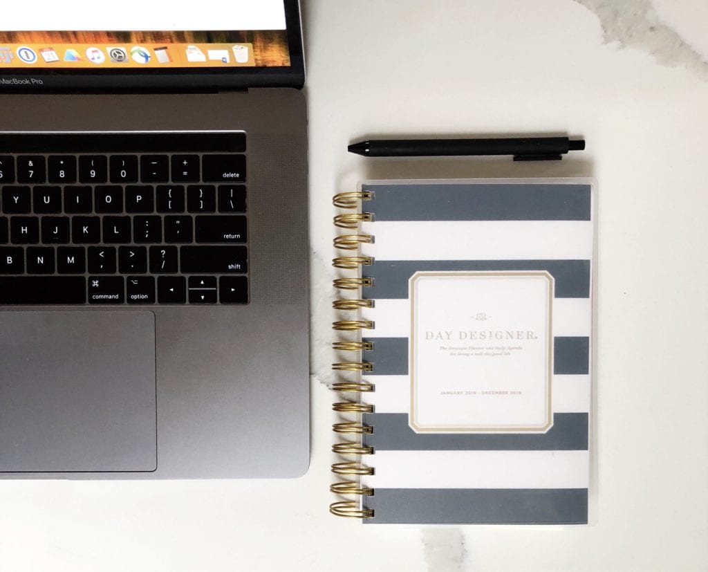 A photo taken from above of the right side of a laptop with a black and white journal beside it. A pen is laid above the journal. Image reflects my advice to cut the cord with fast fashion.