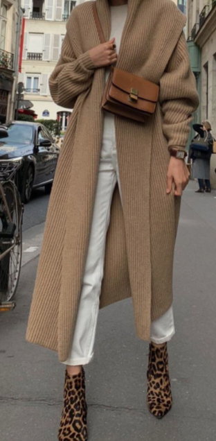 The second Pinterest inspired outfit inspiration. A woman is wearing a long beige cardigan over a white top and white pants. She is wearing black and brown leopard print boots and has a tan cross body bag across her chest.