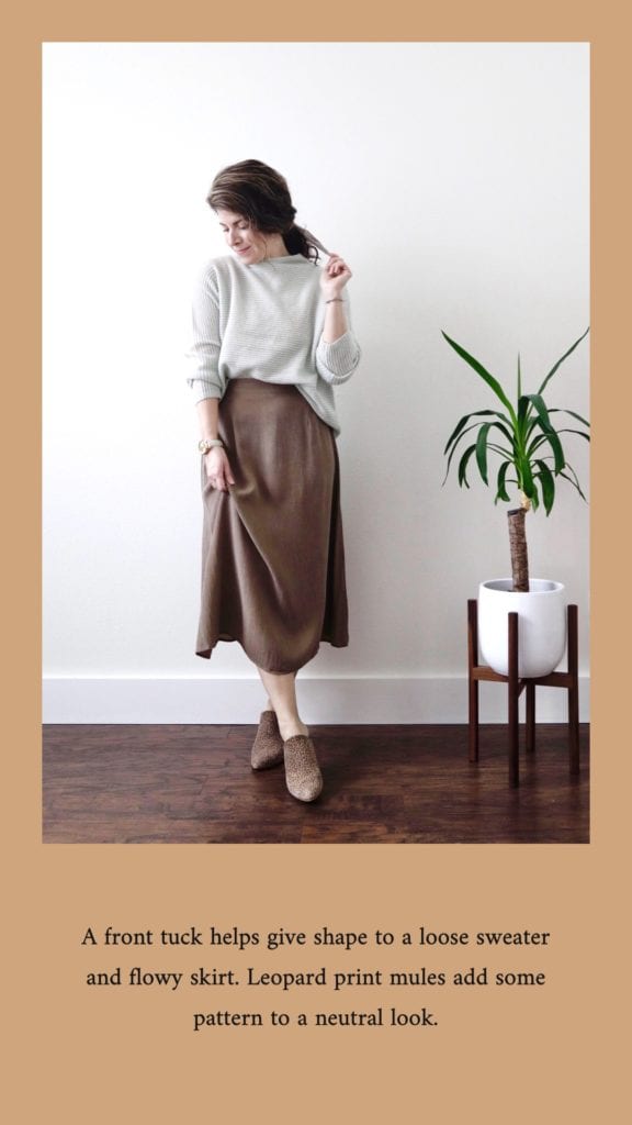 The first outfit from my mini capsule wardrobe. I am wearing a pale green sweater front tucked into a tan midi length skirt. I am wearing leopard print mules and my hair is tied back with a scarf.