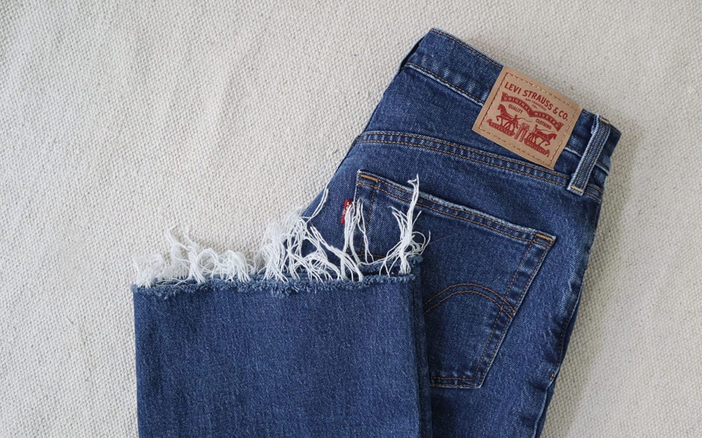 A partial photo of a a pair of blue jeans that show a raw hem that I diy'd.