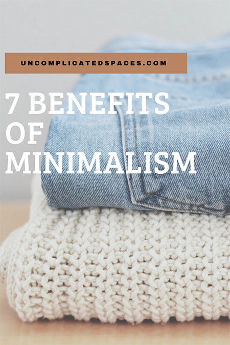 A closeup of a folded pair of light blue jeans on top of a folded cream colored sweater. The words "7 benefits of minimalism" are overlaid on top of the image.