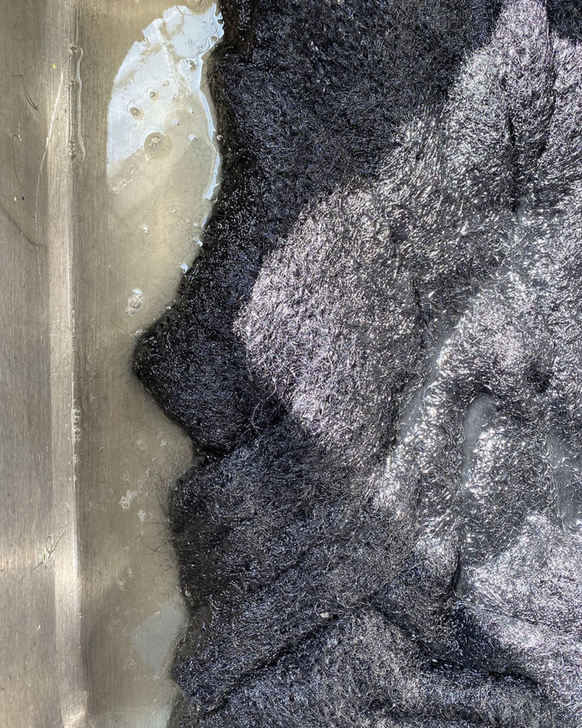 A partial image of the sweater after it has been soaking for a half hour to show how dirty the water is. Could this be the mothball smell washing away?