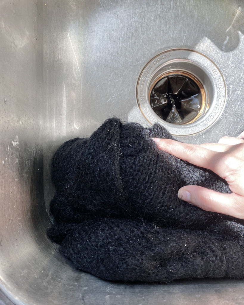 After the first wash. The sink is empty and a woman's hand is squeezing the water out.