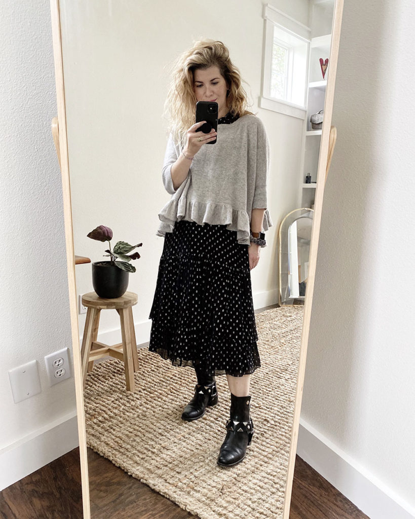 Sweater Outfit 1 - a mirror selfie of a white woman with wavy blonde hair wearing a loose grey sweater with a ruffled hem over a black ruffled midi length dress with ruffles and silver polka dots. she is wearing black moto boots with silver detailing. The next 3 photos are closeups or different angles.
