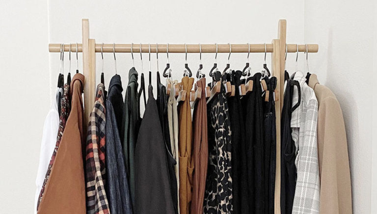 A partial photo of my capsule wardrobe showing 20 items on a wooden clothing rack.