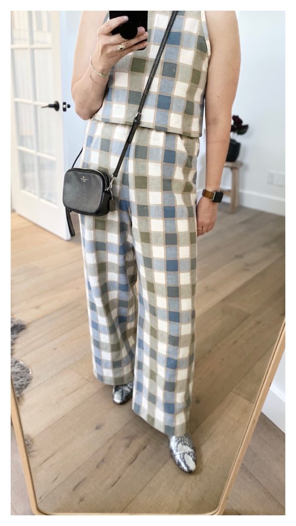 A mirror selfie of the bottom part of the checkered outfit but also showing a small silver crossbody bag that the woman is wearing.