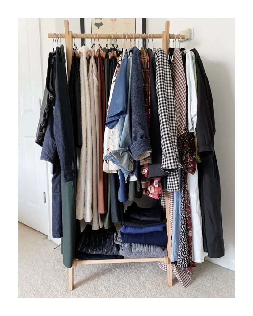 A light toned wooden clothing rack that contains all of the items for my colorful fall capsule wardrobe.
